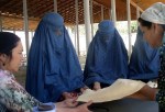 Tajik women teach veiled Afghan women how to bake traditional bread in a tandoor oven in Darvoz, Tajikistan, in June. [Central Asia Online/Nadin Bahrom]