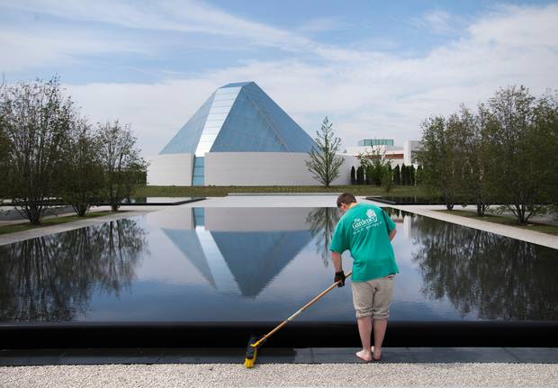 The Ismaili Centre is reflected in a pool as a landscaper works in Aga Khan Park in Toronto. (Darren Calabrese for The Globe and Mail)