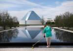 The Ismaili Centre is reflected in a pool as a landscaper works in Aga Khan Park in Toronto. (Darren Calabrese for The Globe and Mail)