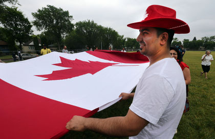 Jihad Ahmed help carry a giant Canadian flag at the 18th annual NorQuest College Canada Day celebrations in Edmonton, Alberta Tuesday, June 30, 2015. Perry Mah/Edmonton Sun/Postmedia Network