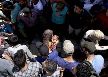 Syrian men form a safety passage for women following clashes during a registration procedure in the national stadium of the Greek island of Kos
