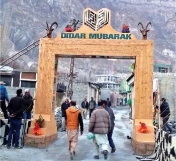 People walk through the special gate of Didargah in Aliabad, Hunza, on Sunday. — Dawn