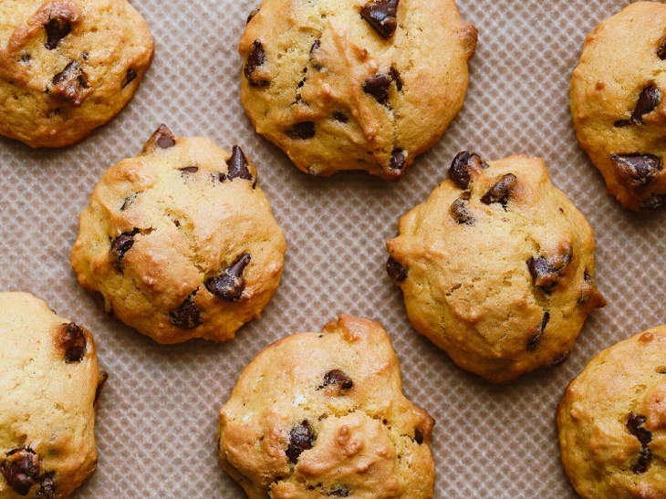 Homemade pumpkin cookies with chocolate chips made from cake mix on a baking sheet. Top view, flat lay.
